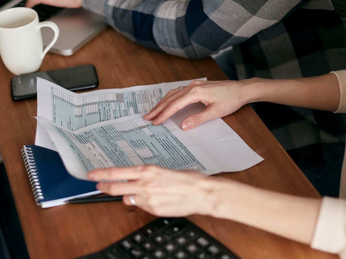 serv-7-credito Pessoa analisando documentos e planilhas de crédito sobre a mesa